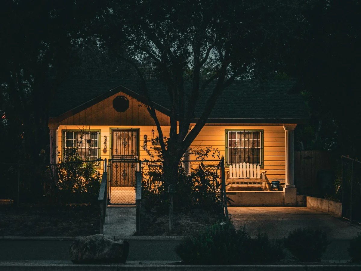 An illuminated modern home glowing at night during a grid blackout to demonstrate how solar panels work during a power outage with battery backup.