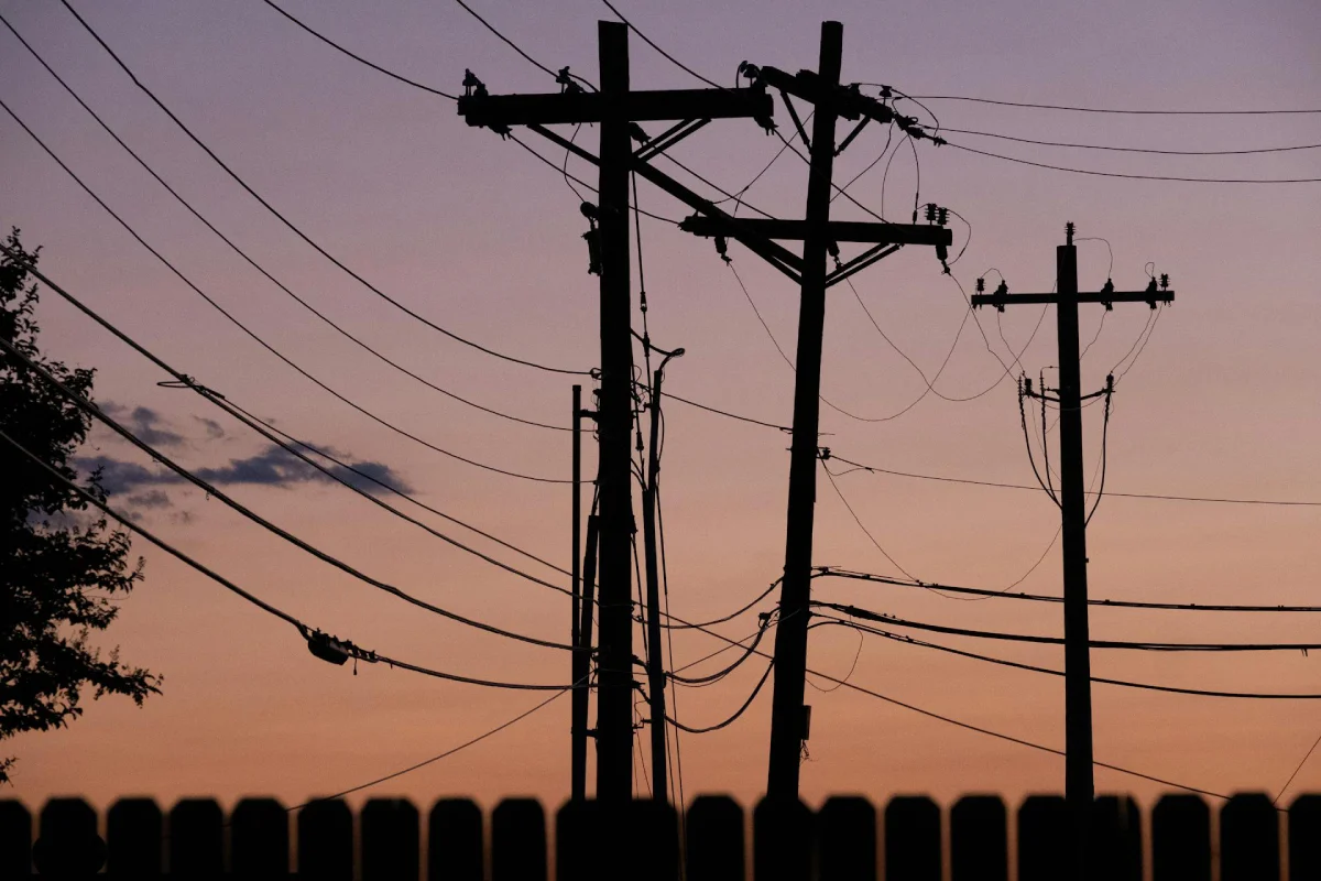 A silhouette of utility lines at sunset, highlighting the need for the best portable power stations for home backup when the local grid becomes unreliable.