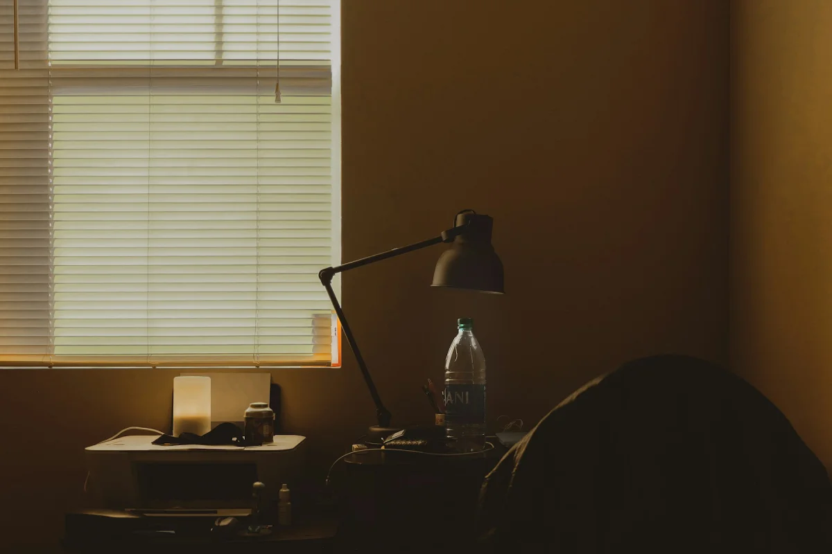 A dark home office desk with a lamp, showcasing the top-rated emergency battery backup solutions needed to keep essential electronics running during a blackout.