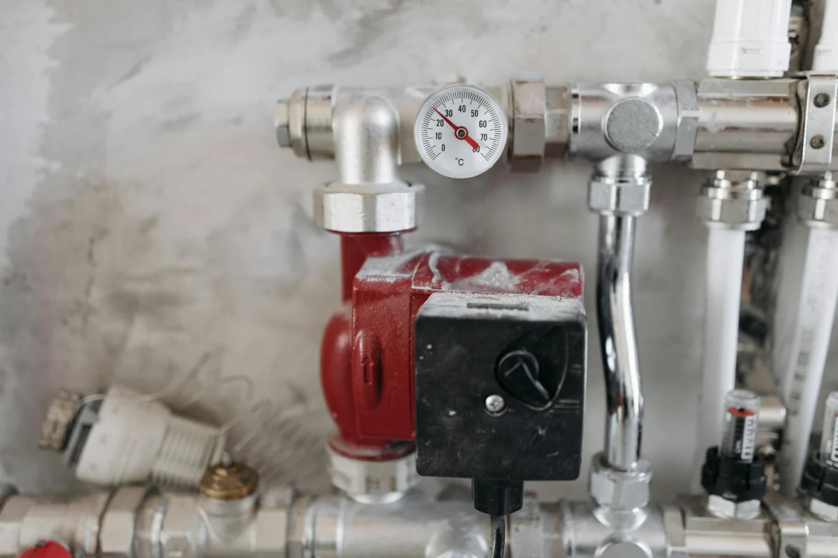 Basement plumbing and pressure gauge connected to a portable power station for sump pump backup during a power outage.