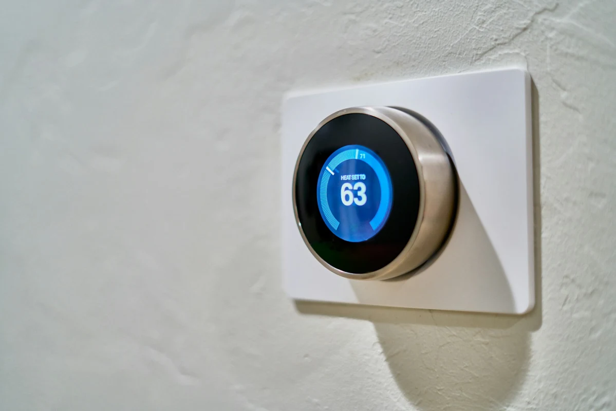 A close-up of a modern smart thermostat mounted on a clean white wall, displaying a 68°F energy-saving setting and an "Eco" leaf icon to illustrate home energy efficiency and HVAC cost reduction.