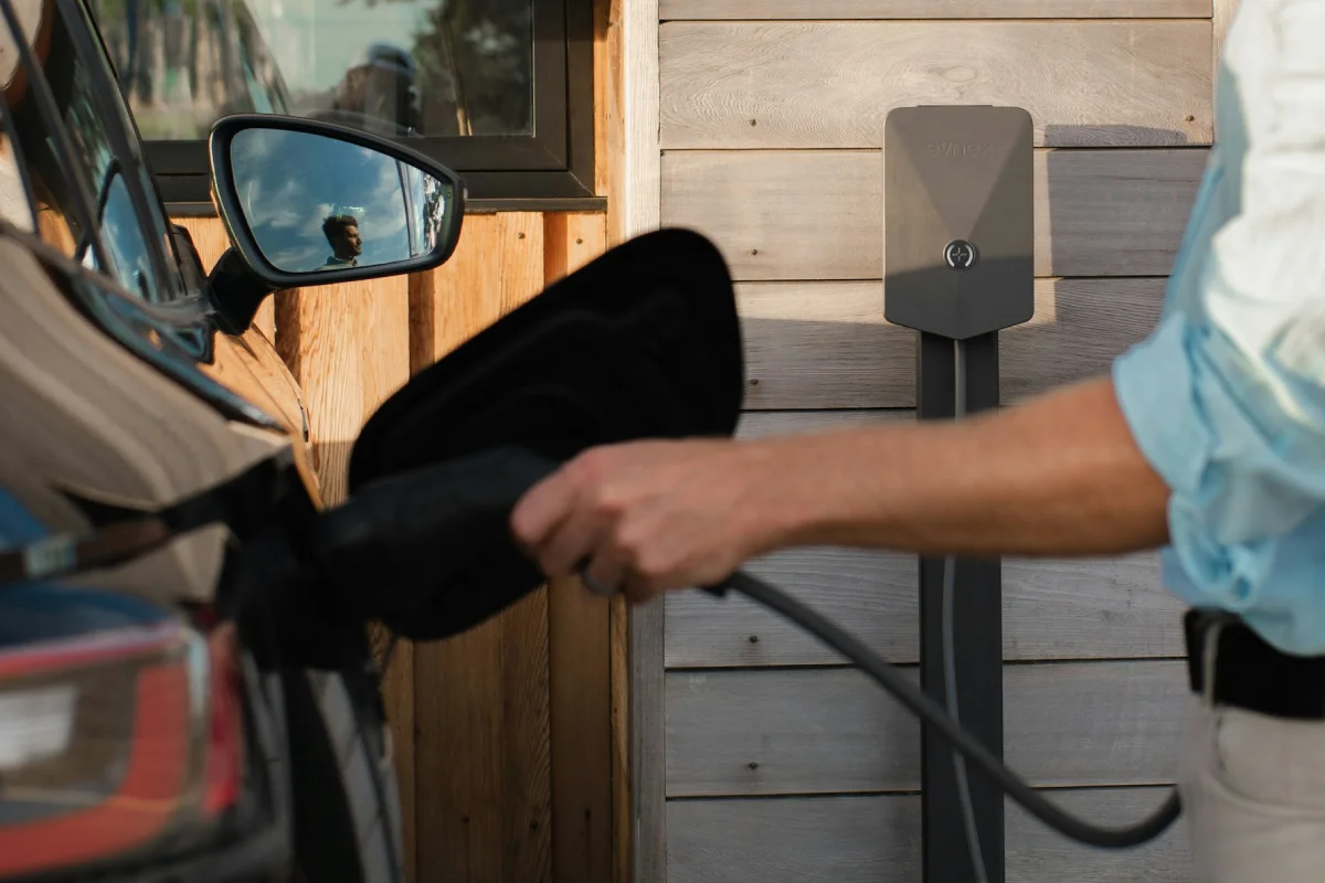 A close-up shot of a hand lifting a heavy-duty charger handle to manage electric vehicle charging installation.