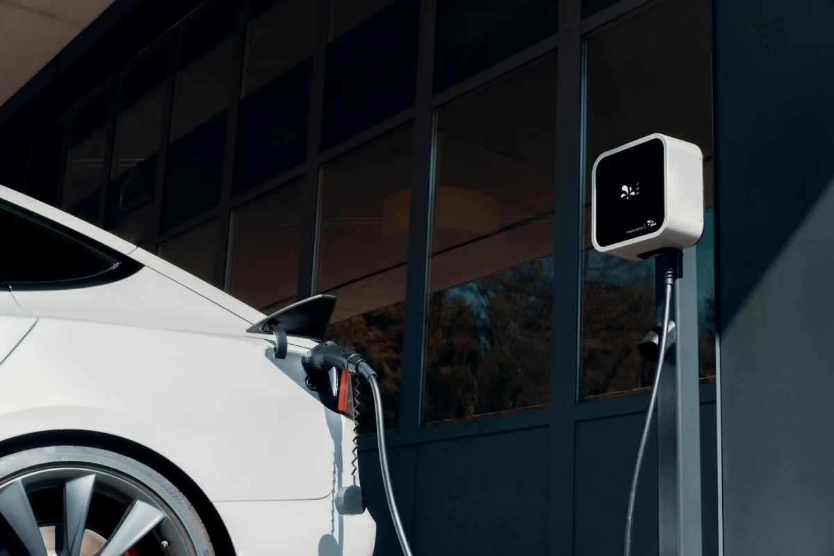 A white electric vehicle plugged into a charger, showcasing a clean EV charging setup.
