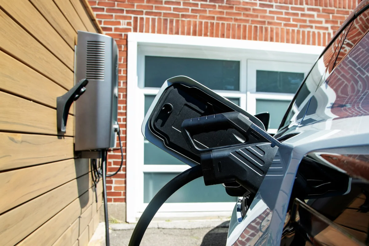 A smart wallbox charging unit mounted on a wooden wall, serving as a dedicated home EV charging station.