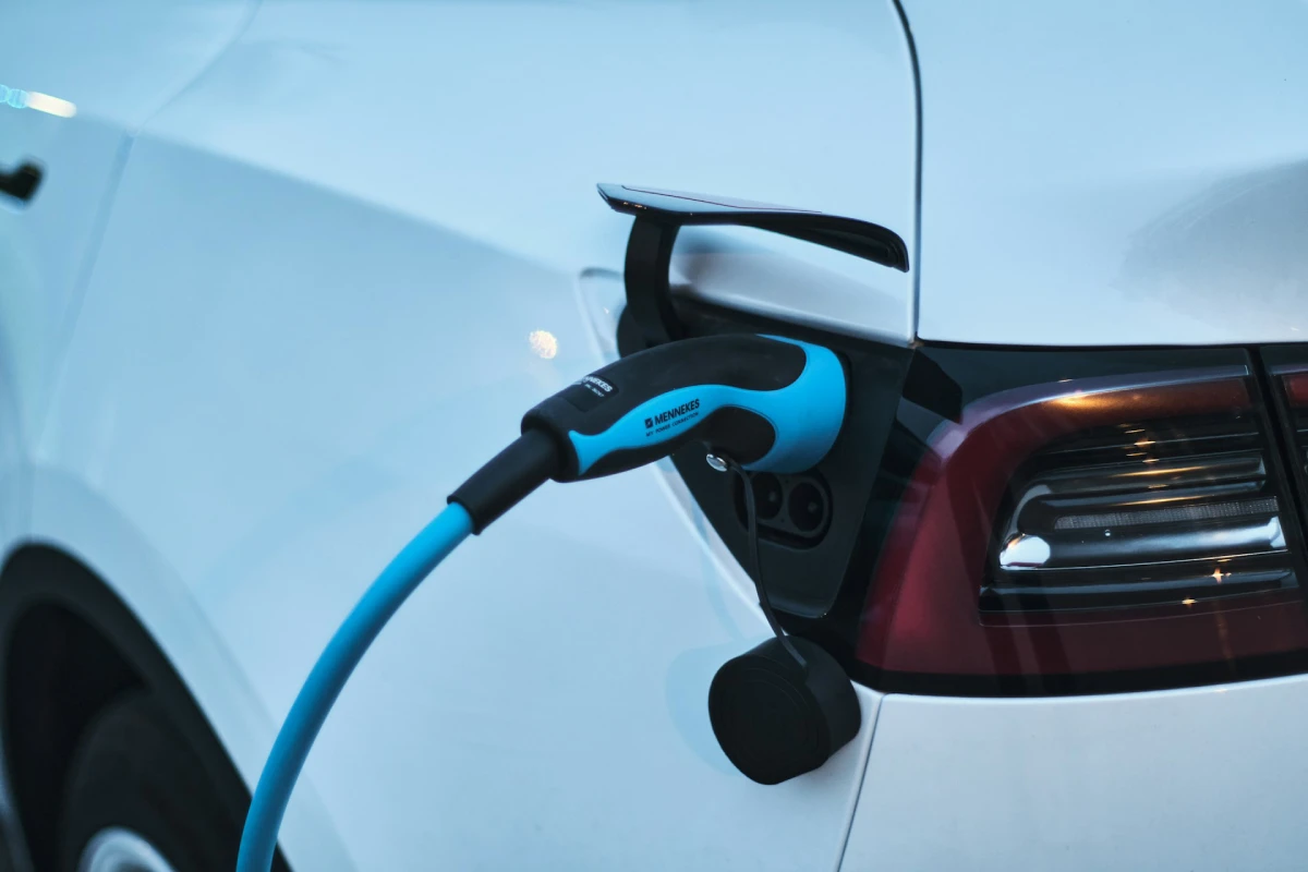 A blue electric car parked outdoors while connected to a fast Level 2 charger installation.